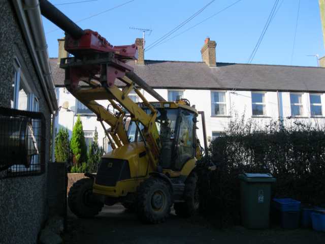 JCB edges in from lane with new pole swung over kitchen roof